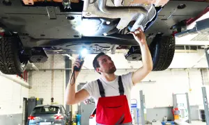Mechanik bada podwozie auta, szukając przyczyny zapachu spalonego sprzęgła.