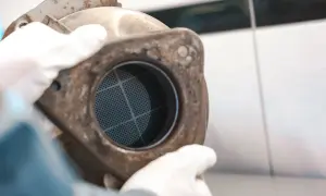 Ręce w białych rękawiczkach trzymają zardzewiały element z siatką. Może to być część procesu, jak wypalić dpf podczas jazdy.