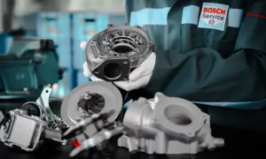 Mechanik w rękawiczkach prezentuje turbosprężarkę. Dowiedz się, jak wydłużyć żywotność turbosprężarki w silniku z start-stop.
