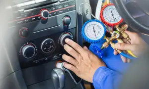Sprawdzanie drożności chłodnicy klimatyzacji domowym sposobem. Mechanik podłącza manometry do układu klimatyzacji w samochodzie.