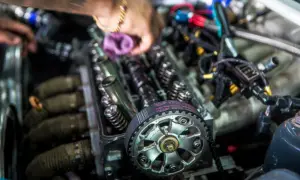 Mechanik pracuje przy silniku, pokazując różnicę między silnikiem kolizyjnym a bezkolizyjnym. Widoczny pasek rozrządu i zawory.