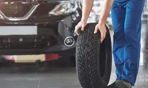 Mechanik pokazuje, jak założyć opony kierunkowe. Widać bieżnik z charakterystycznym wzorem.