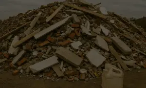 Góra gruzu budowlanego, cegieł i desek. Plastikowy kanister na pierwszym planie. To przypomina, dlaczego serwisy oponiarskie doliczają opłatę za utylizację ciężarków ołowianych.