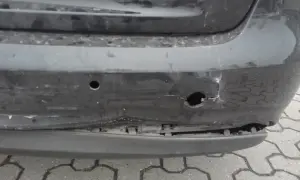 Uszkodzony zderzak po uderzeniu parkingowym: wgniecenia, pęknięcia i widoczne objawy uszkodzonych ślizgów zderzaka.