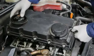 Mechanik w białych rękawiczkach sprawdza silnik turbo, szukając objawów uszkodzonej odmy olejowej.