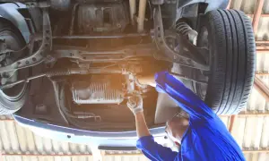 Mechanik reguluje przekładnię kierowniczą, aby usunąć luz na śrubie regulacyjnej. Naprawa zawieszenia samochodu.