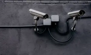 Dwie kamery monitoringu na szarej ścianie. Czy to tylko bezpieczeństwo, czy może coś więcej?