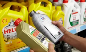 Ręce wybierają jaki olej silnikowy: Castrol EDGE i Mobil Super. W tle żółte kanistry Shell Helix.