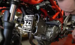 Mechanik sprawdza zawory motocykla, przygotowując się do zadania: jak samodzielnie ustawić luzy zaworowe w motocyklu.