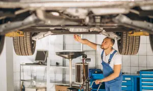 Mechanik sprawdza podwozie auta, zastanawiając się, czy regeneracja maglownicy jest bezpieczna i opłacalna.