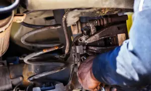 Mechanik przy pracy nad sprężyną amortyzatora. Dowiedz się, jak ścisnąć sprężynę amortyzatora domowym sposobem.