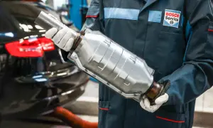 Mechanik w rękawiczkach trzyma katalizator. Usunięcie go w benzynie może wpłynąć na moc silnika, ale też na środowisko.
