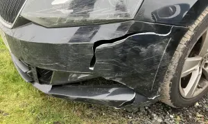 Usunięcie wypełnienia styropianowego spod zderzaka ujawniło pęknięcia i zarysowania na czarnym zderzaku samochodu.