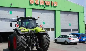 Traktor przed zielonym budynkiem serwisu. Zastanawiasz się, ile kosztuje roboczogodzina mechanika?