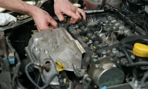 Mechanik pracuje przy silniku, diagnozując objawy uszkodzonego czujnika położenia wałka rozrządu.