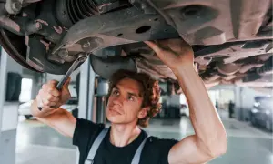 Mechanik naprawia zawieszenie, by uniknąć skutków jazdy z wybitą tuleją wahacza przedniego.