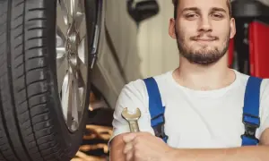 Uśmiechnięty mechanik z kluczem w dłoni, gotowy do pracy przy aucie hybrydowym. To on stoi za nowymi certyfikatami dla mechaników.