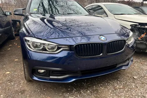 Granatowe BMW z odbiciami drzew na masce. Zastanawiasz się, ile kosztuje lakierowanie zderzaka?