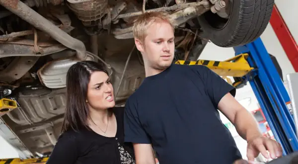 Zirytowana klientka pyta mechanika o ukryte przyczyny dla których każe płacić za diagnostykę komputerową dwa razy.