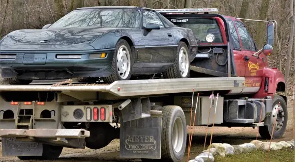 Zielony Chevrolet Corvette na czerwonym samochodzie holowniczym.
