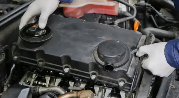 Mechanik w białych rękawiczkach sprawdza silnik turbo, szukając objawów uszkodzonej odmy olejowej.