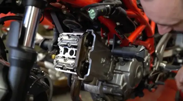 Mechanik sprawdza zawory motocykla, przygotowując się do zadania: jak samodzielnie ustawić luzy zaworowe w motocyklu.