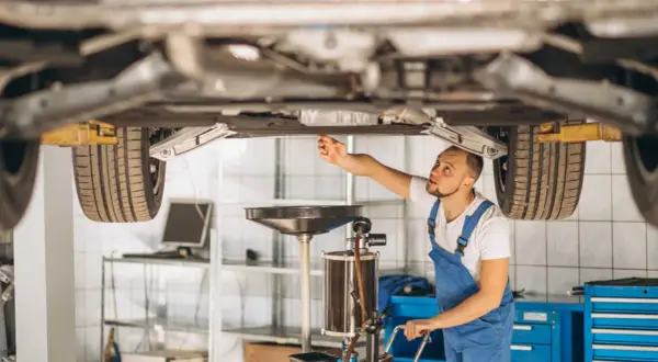 Mechanik sprawdza podwozie auta, zastanawiając się, czy regeneracja maglownicy jest bezpieczna i opłacalna.