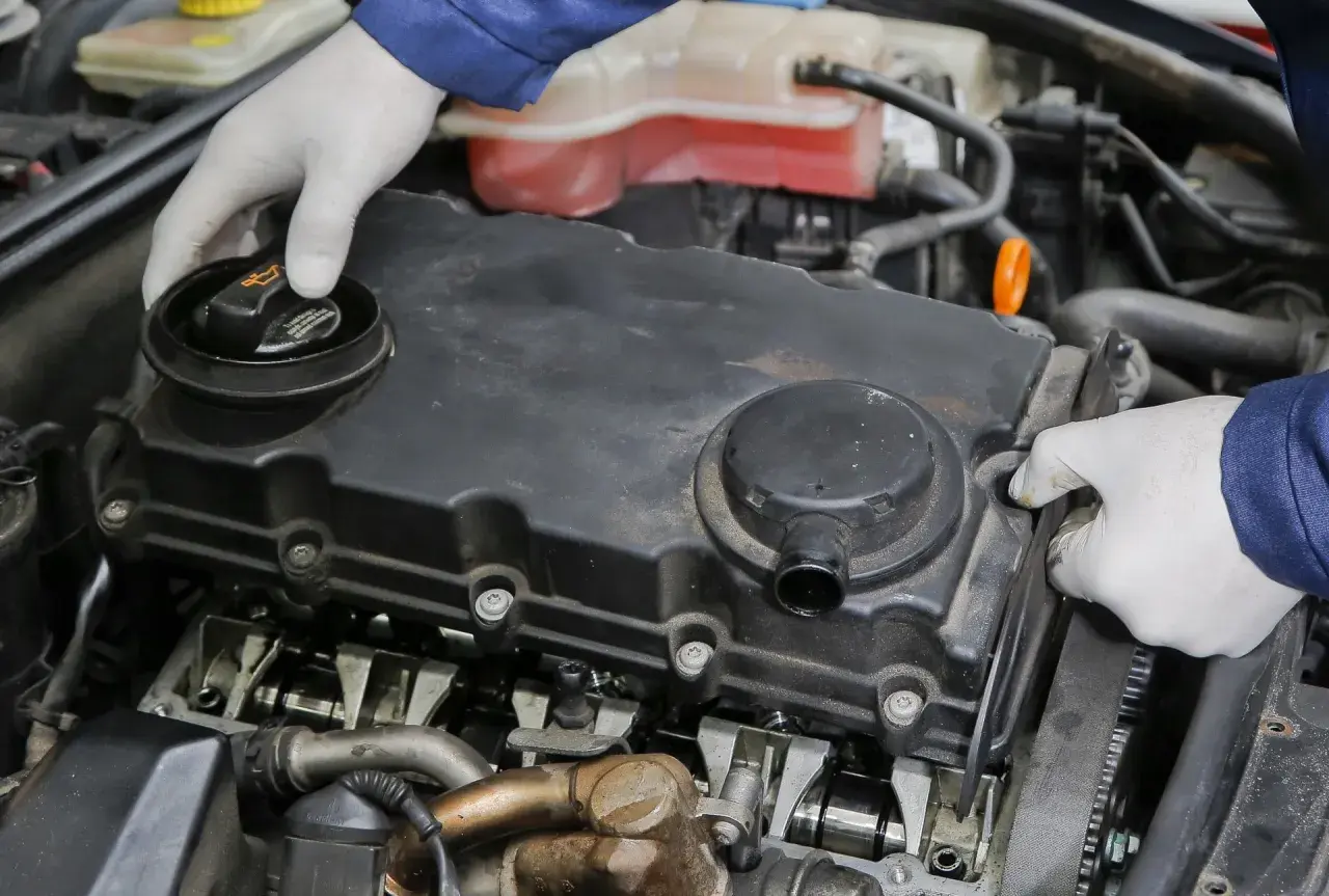 Mechanik w białych rękawiczkach sprawdza silnik turbo, szukając objawów uszkodzonej odmy olejowej.