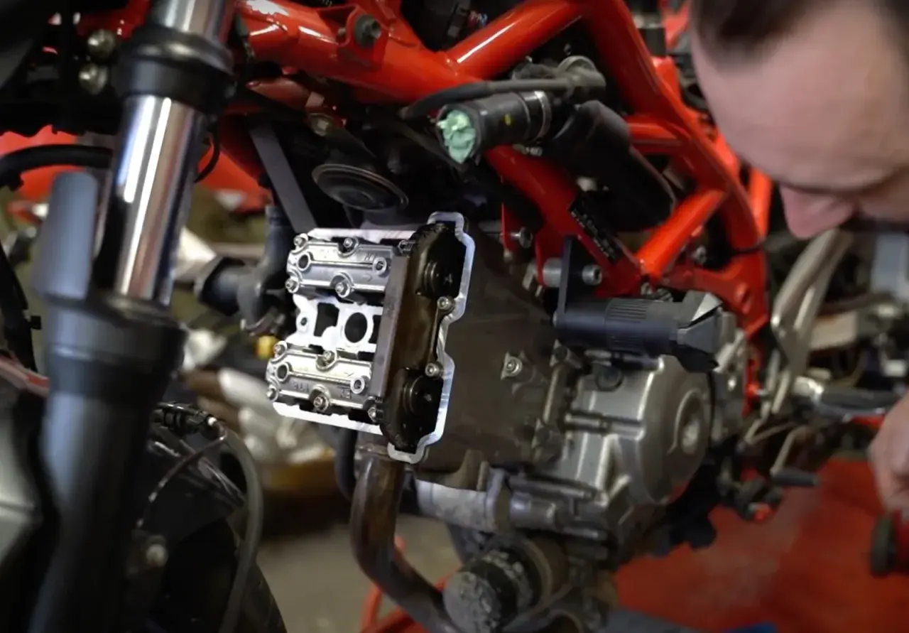 Mechanik sprawdza zawory motocykla, przygotowując się do zadania: jak samodzielnie ustawić luzy zaworowe w motocyklu.