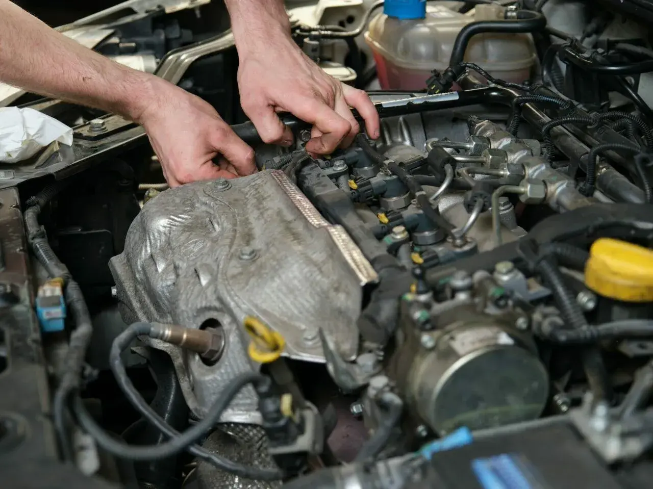 Mechanik pracuje przy silniku, diagnozując objawy uszkodzonego czujnika położenia wałka rozrządu.