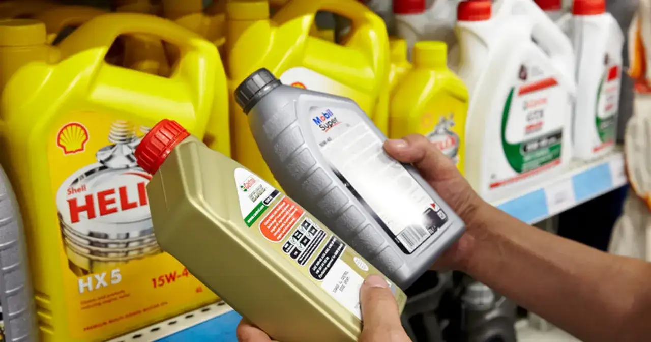 Ręce wybierają jaki olej silnikowy: Castrol EDGE i Mobil Super. W tle żółte kanistry Shell Helix.