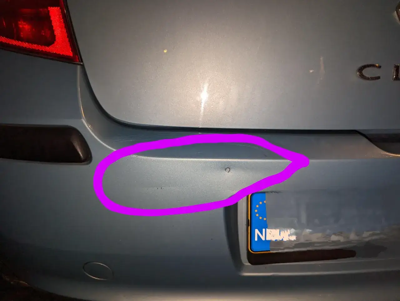 Jak wyprostować wgniecenie w zderzaku za pomocą gorącej wody? Na zdjęciu widać wgniecenie na niebieskim zderzaku samochodu, zaznaczone fioletową obwódką.