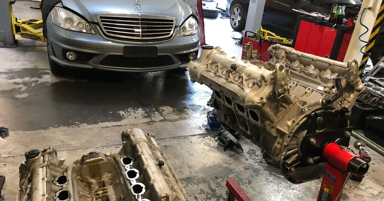 Warsztat samochodowy: skutki przegrzania silnika aluminiowego a żeliwnego. Dwa silniki Mercedesa na podnośnikach.