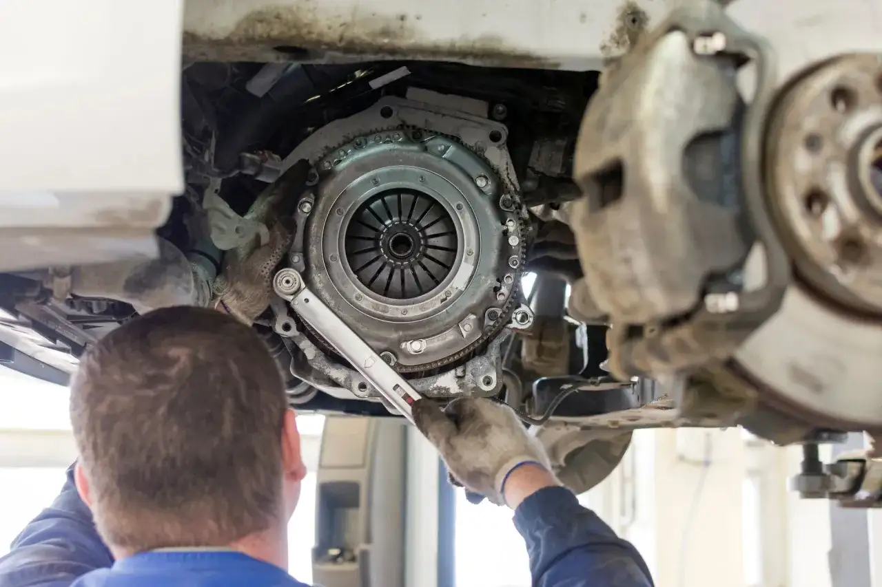 Mechanik dokręca śruby docisku sprzęgła, pokazując, jak podłączyć sprzęgło hydrauliczne. Widoczny jest też hamulec.