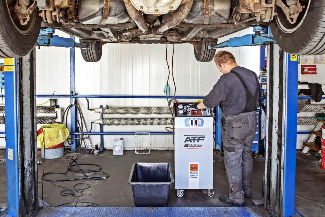 Mechanik przy maszynie do dynamicznej wymiany oleju w skrzyni automatycznej. Dowiedz się, ile kosztuje dynamiczna wymiana oleju w skrzyni automatycznej w 2026 roku.