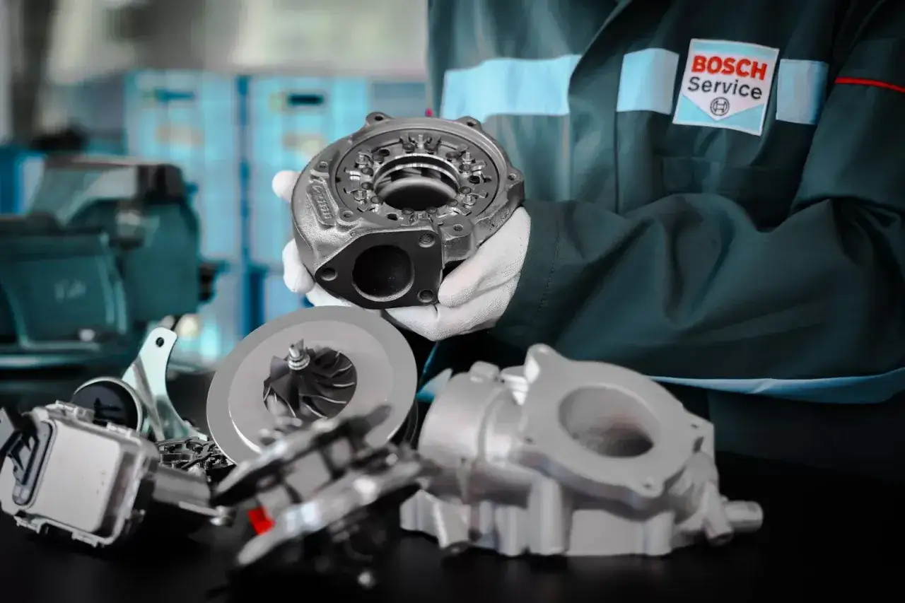 Mechanik w rękawiczkach prezentuje turbosprężarkę. Dowiedz się, jak wydłużyć żywotność turbosprężarki w silniku z start-stop.