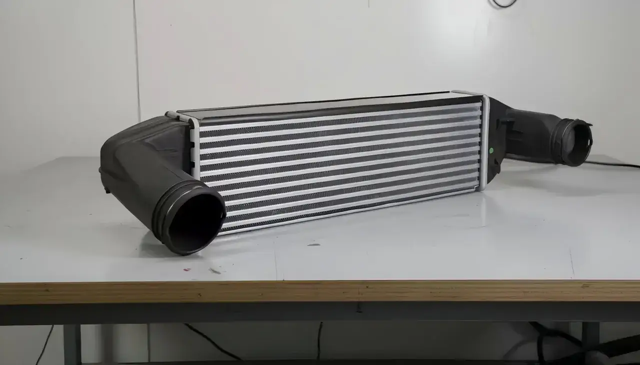 Intercooler samochodowy z czarnymi wlotami. Sprawdź, jak sprawdzić, czy turbina puszcza olej do intercoolera, analizując jego stan.