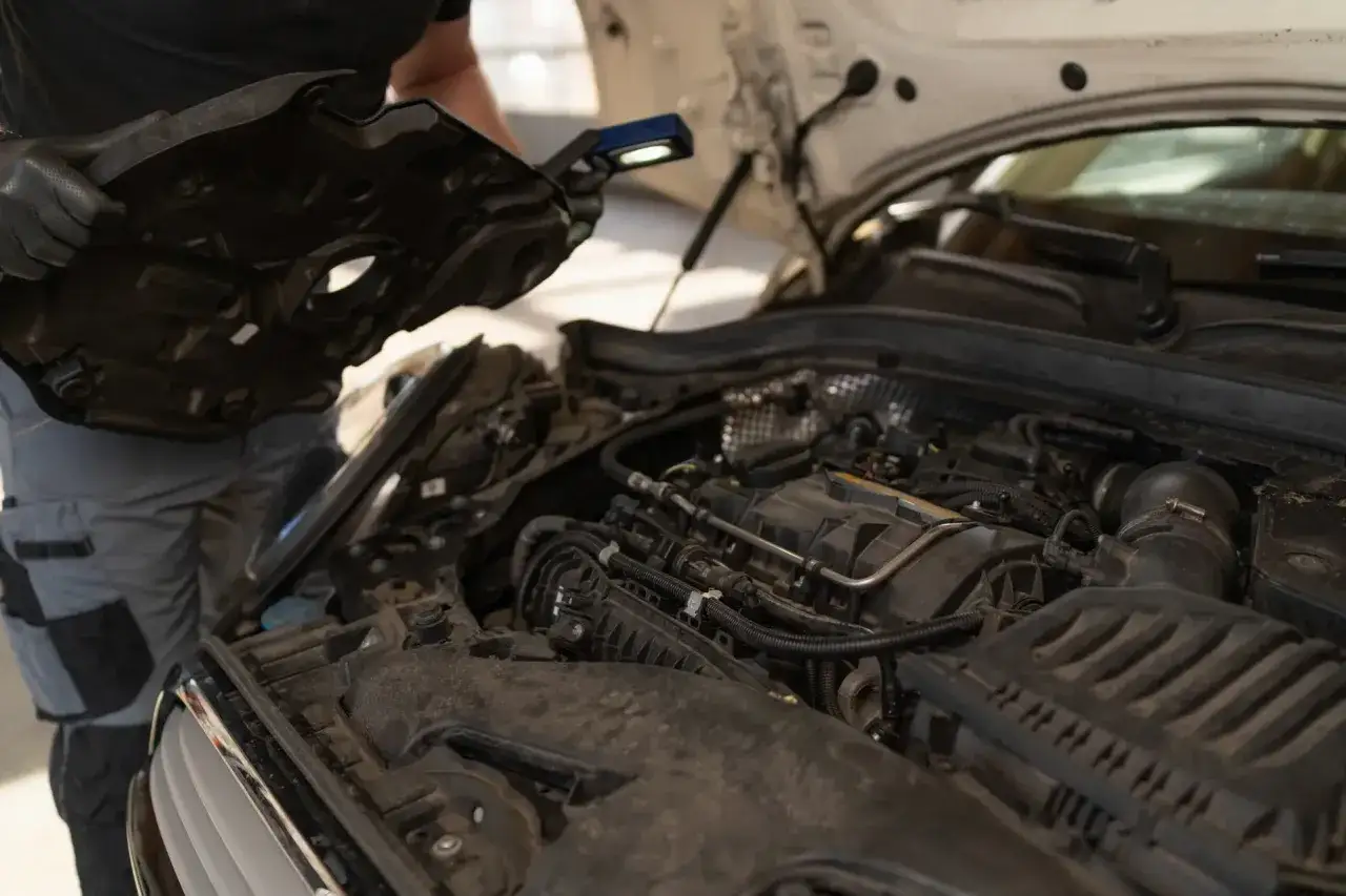 Mechanik sprawdza silnik, szukając przyczyn, dlaczego ubywa płynu chłodniczego, a nie ma wycieku.