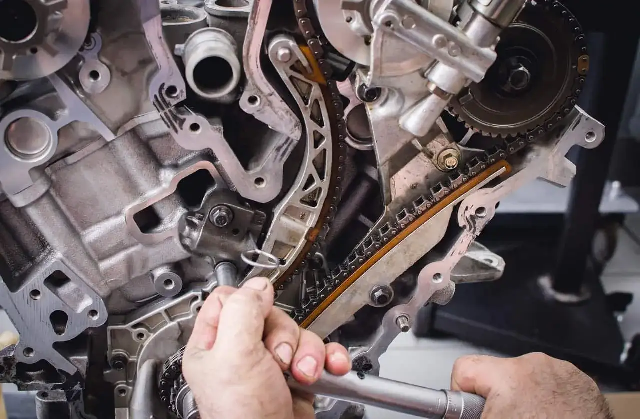 Mechanik sprawdza napinacz łańcucha rozrządu, kluczowy element w procesie jak sprawdzić poduszki silnika.