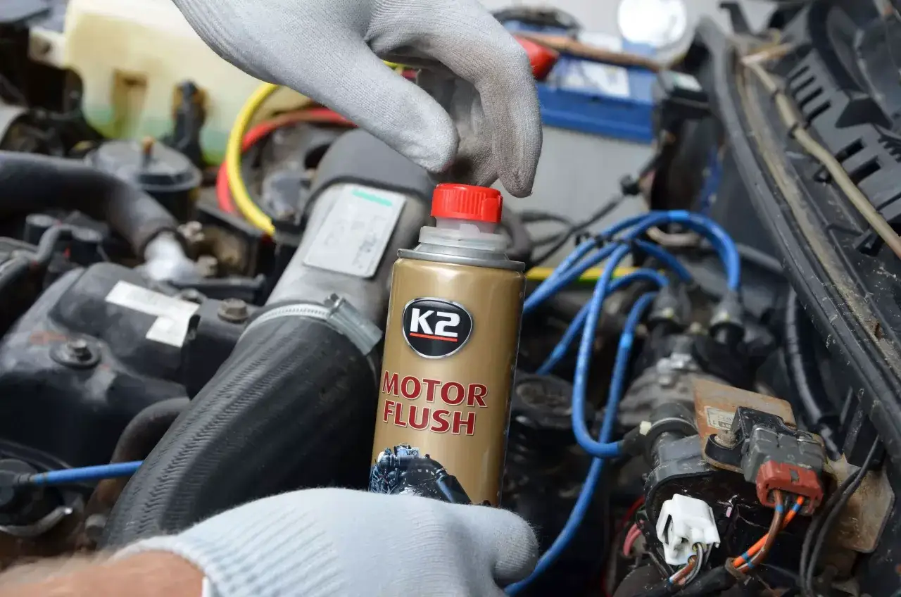 Ręka w rękawiczce otwiera puszkę K2 Motor Flush. Czy płukanka silnika engine flush może rozszczelnić stary silnik?