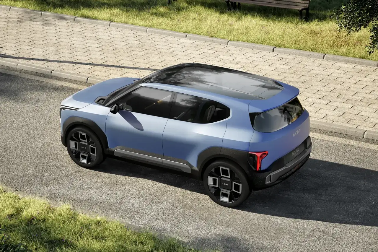 Niebieski, futurystyczny SUV Kia EV2, który od 2026 r. każdy serwis musi oferować zastępcze auto elektryczne, stoi na tle chodnika i trawy.