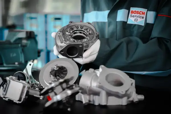 Mechanik w rękawiczkach prezentuje turbosprężarkę. Dowiedz się, jak wydłużyć żywotność turbosprężarki w silniku z start-stop.