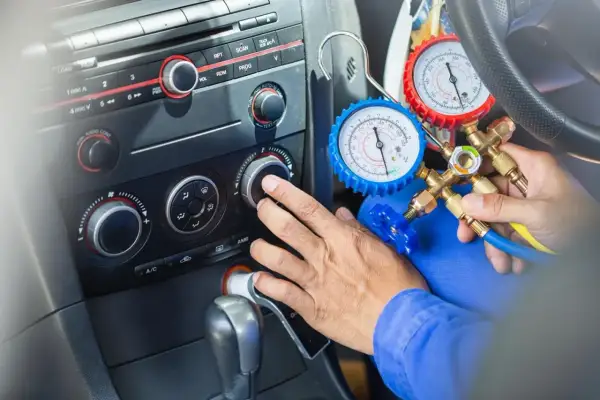 Sprawdzanie drożności chłodnicy klimatyzacji domowym sposobem. Mechanik podłącza manometry do układu klimatyzacji w samochodzie.