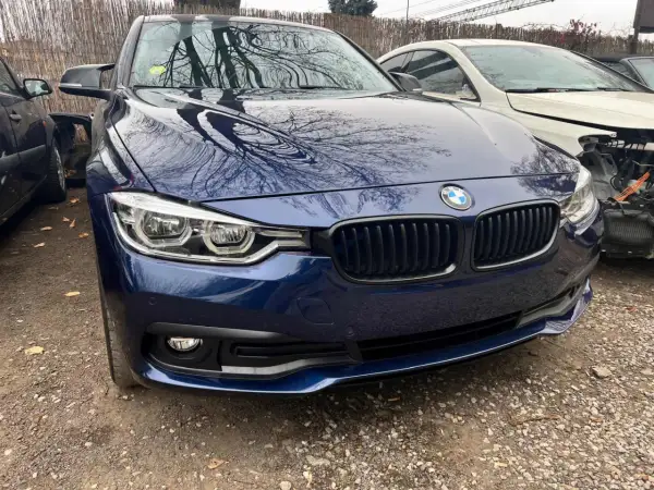 Granatowe BMW z odbiciami drzew na masce. Zastanawiasz się, ile kosztuje lakierowanie zderzaka?