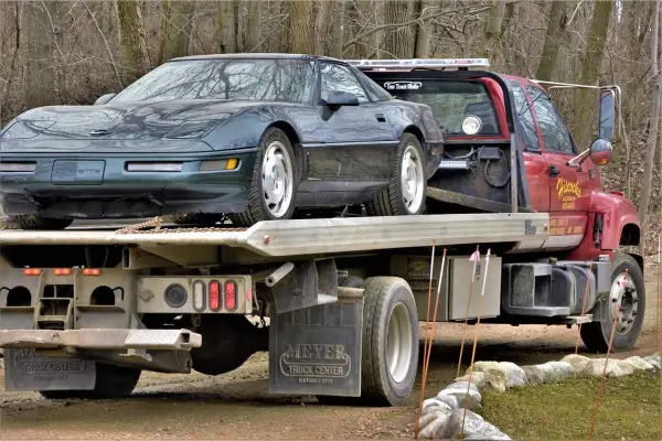 Zielony Chevrolet Corvette na czerwonym samochodzie holowniczym.