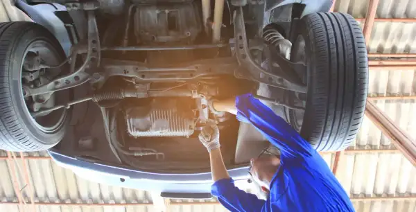 Mechanik reguluje przekładnię kierowniczą, aby usunąć luz na śrubie regulacyjnej. Naprawa zawieszenia samochodu.