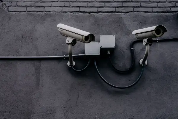Dwie kamery monitoringu na szarej ścianie. Czy to tylko bezpieczeństwo, czy może coś więcej?