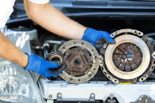 Mechanik pokazuje zużyte części: sprzęgło i dwumasę. Dowiedz się, ile kosztuje wymiana sprzęgła i dwumasy.