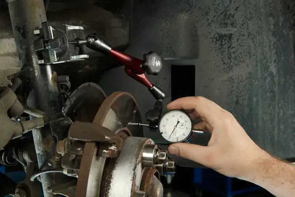 Mechanik mierzy bicie tarczy hamulcowej, co może być jedną z przyczyn bicia kierownicy przy hamowaniu z dużej prędkości.